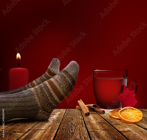 Füße auf dem Tisch mit Glühwein und Kerze