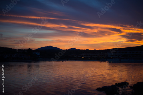 sunset cloudscape with orange and blue clouds over the coastline of Golfo Aranci, Sardinia,Italy