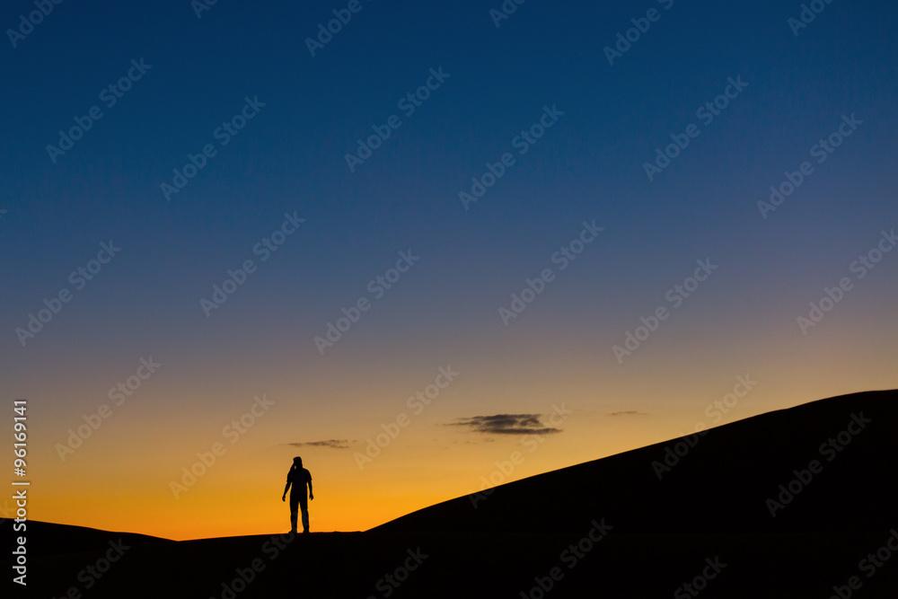 Sillhouette of man in desert at sunset
