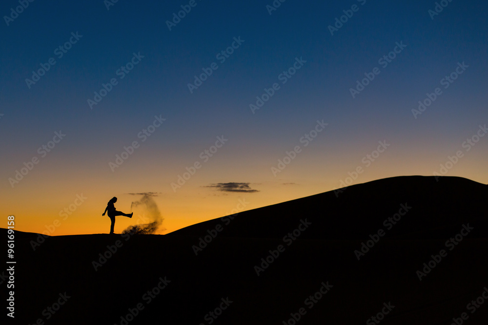 Man playing with sands in desert at sunset