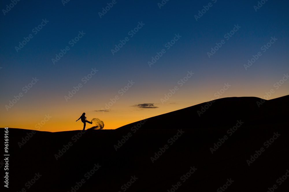 Man playing with sands in desert at sunset