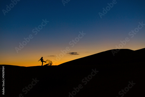 Man playing with sands in desert at sunset