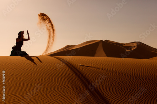 Sillhouette woman playing and throwing with sands in Desert Saha