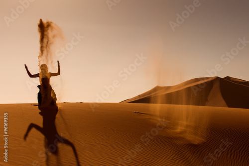 Sillhouette of woman playing and throwing with sands in Desert S photo