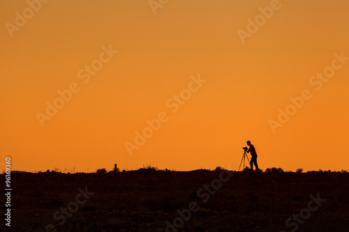 Silhouette of photographer during sunset with tripod © danmir12