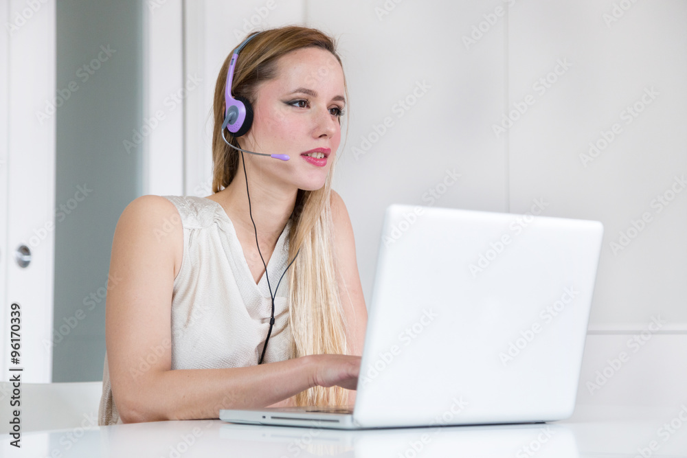 Attractive blonde woman with headset working on a laptop. Attractive blonde woman with headset working on a laptop.