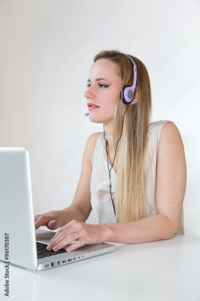 Attractive blonde woman with headset working on a laptop. Attractive blonde woman with headset working on a laptop.
