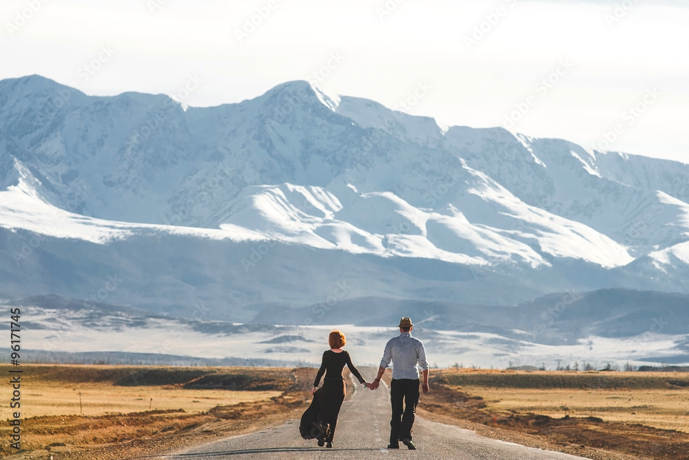 The girl and the guy are on the road in the mountains The girl and the guy are on the road in the mountains