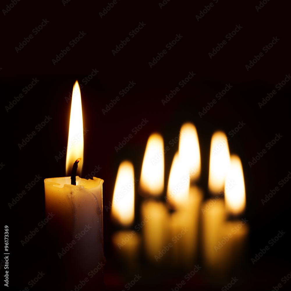 single burning candle and a group of other candles blurred in th Stock  Photo | Adobe Stock