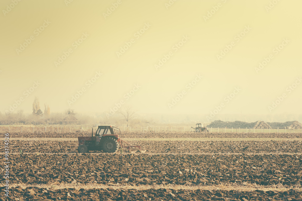 Obraz premium Retro toned tractors on arable field