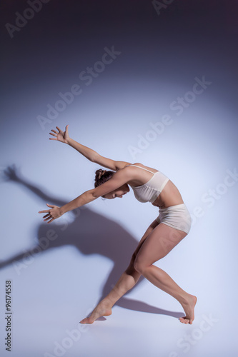 Fototapeta Naklejka Na Ścianę i Meble -  Young beautiful dancer in beige swimwear dancing on lilac background