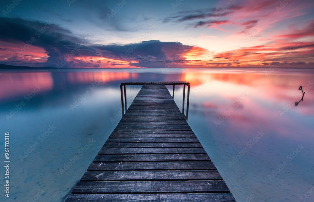 romantic sunset colour with reflection and wooden jetty as foreground