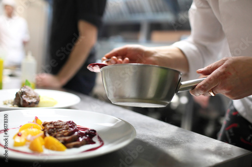 Fototapeta Naklejka Na Ścianę i Meble -  Chef is decorating delicious dish, motion blur on hands