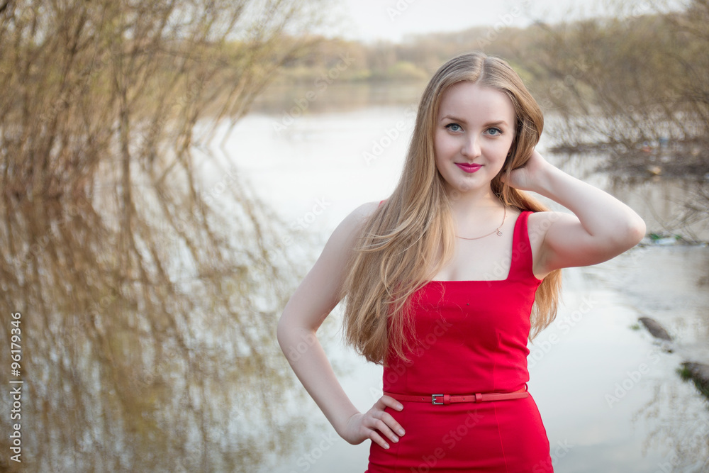Blonde woman in red dress posing outdoors