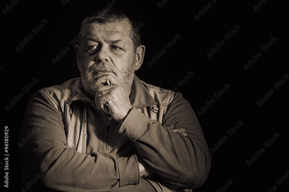 Nice sepia toned image of a pensive senior man  against dark  background
