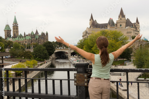 Young woman tourist with arms up, back to camera in Ottawa, Cana