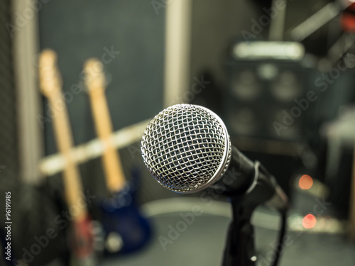 Selective focus on microphone with blurry music studio backgroun