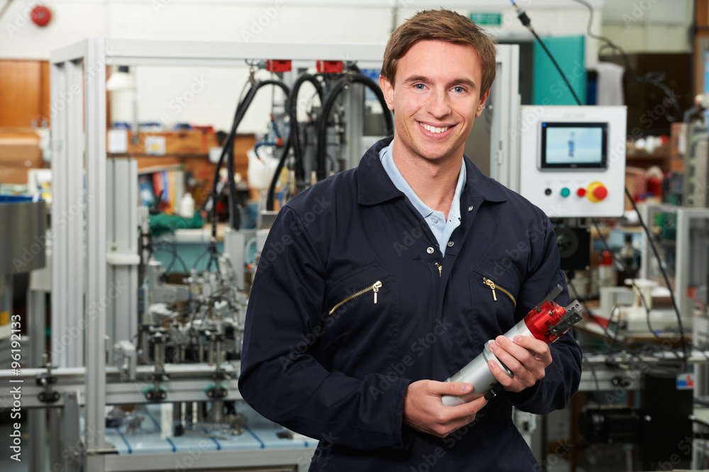 Portrait Of Engineer Holding Component In Factory Portrait Of Engineer Holding Component In Factory