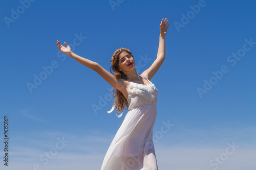 Young brunette in white flimsy dress enjoys the summer sun.