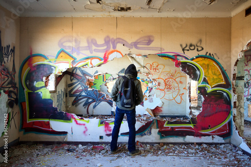 Un homme de dos au dans un bâtiment rempli de graffitis