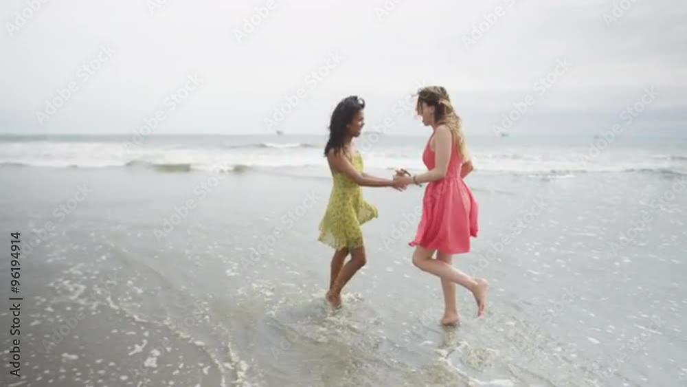 Cute girlfriends running around at the beach smiling Cute girlfriends running around at the beach smiling