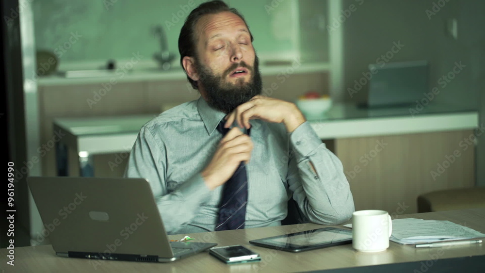 Sad, tired businessman working with laptop in office
Sad, tired businessman working with laptop in office