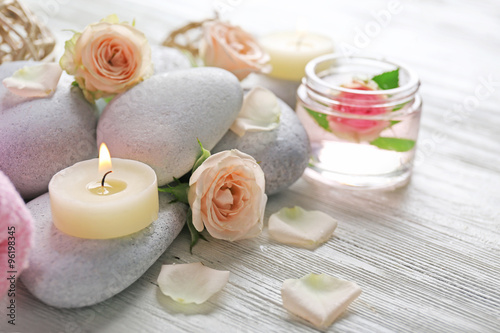 Composition of flowers  candles and stones on white wooden background  in spa salon