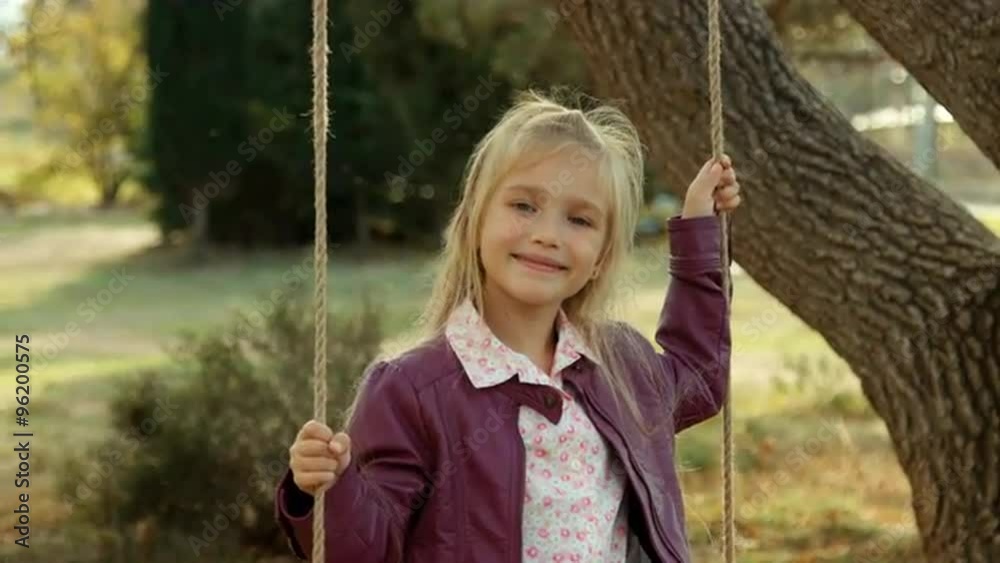 Laughing girl on a swing under a tree in the park Laughing girl on a swing under a tree in the park