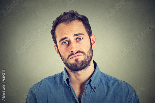 Portrait of a sad young man isolated on gray wall background