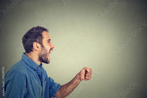 ngry young man screaming with fist up in air