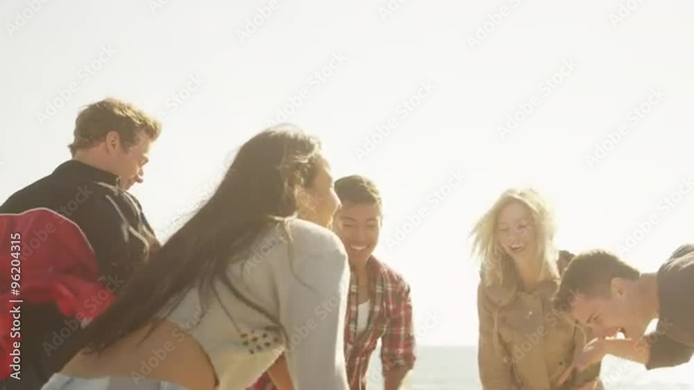 Young adult group of interracial friends dancing on the beach