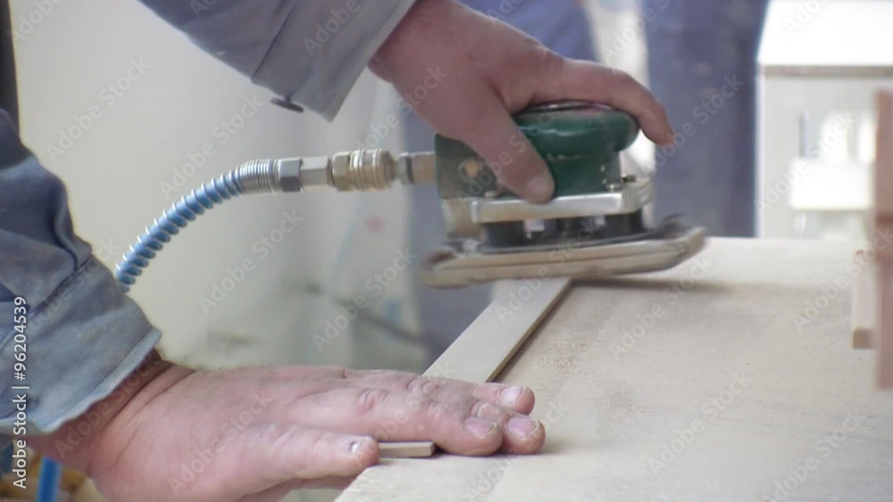 Worker using a power sander to smooth part of the doors frame. Stock