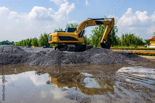 Backhoe standing on stone on construction site.