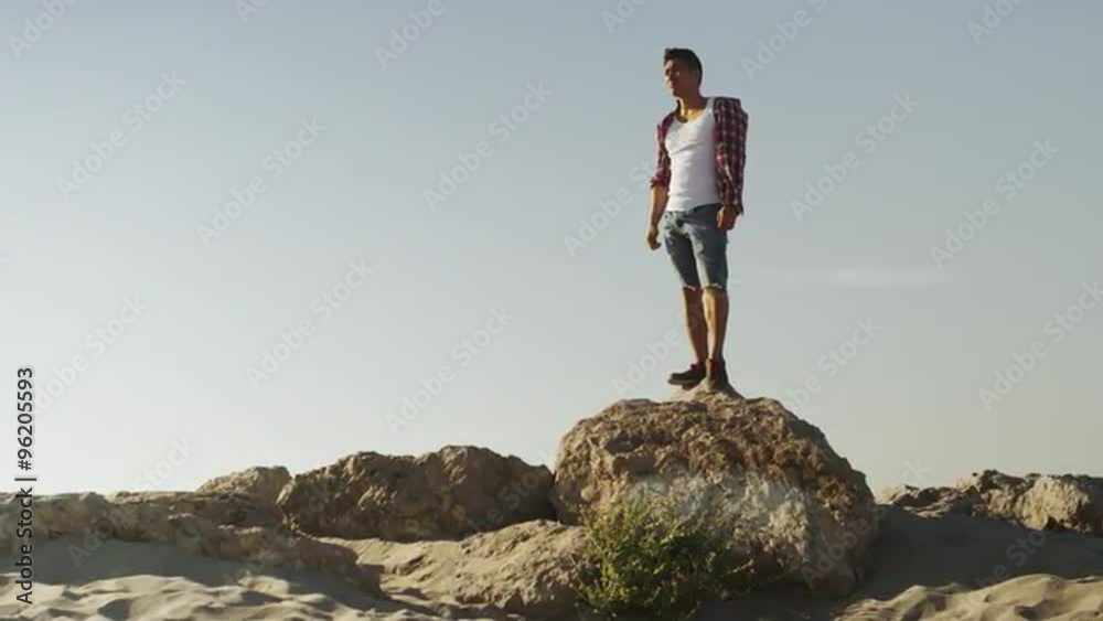 Handsome Asian man standing on top of rock at the beach Handsome Asian man standing on top of rock at the beach