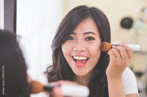 Woman applying on blush on  look at the mirror