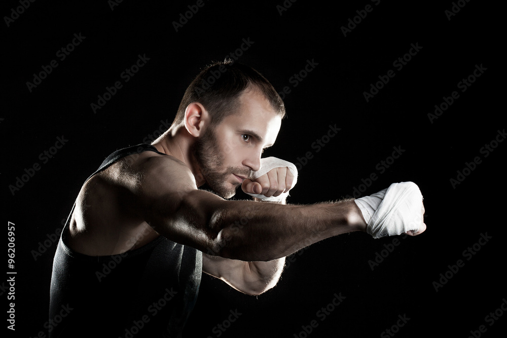 muscular man, tying an elastic bandage on his hand, black background