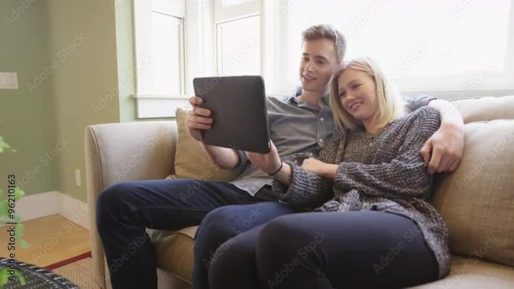 Couple using tablet together on the couch Couple using tablet together on the couch
