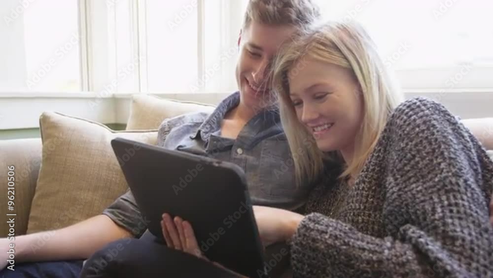 Beautiful couple using tablet together on couch Beautiful couple using tablet together on couch