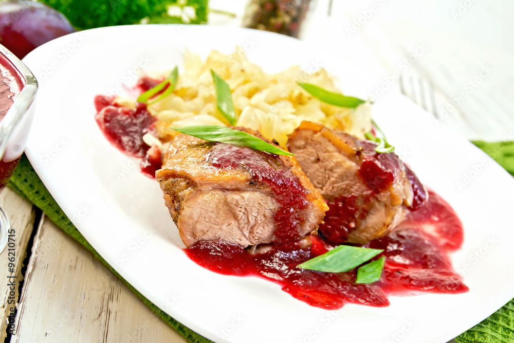Duck breast with plum sauce and cabbage in plate on green napkin Duck breast with plum sauce and cabbage in plate on green napkin