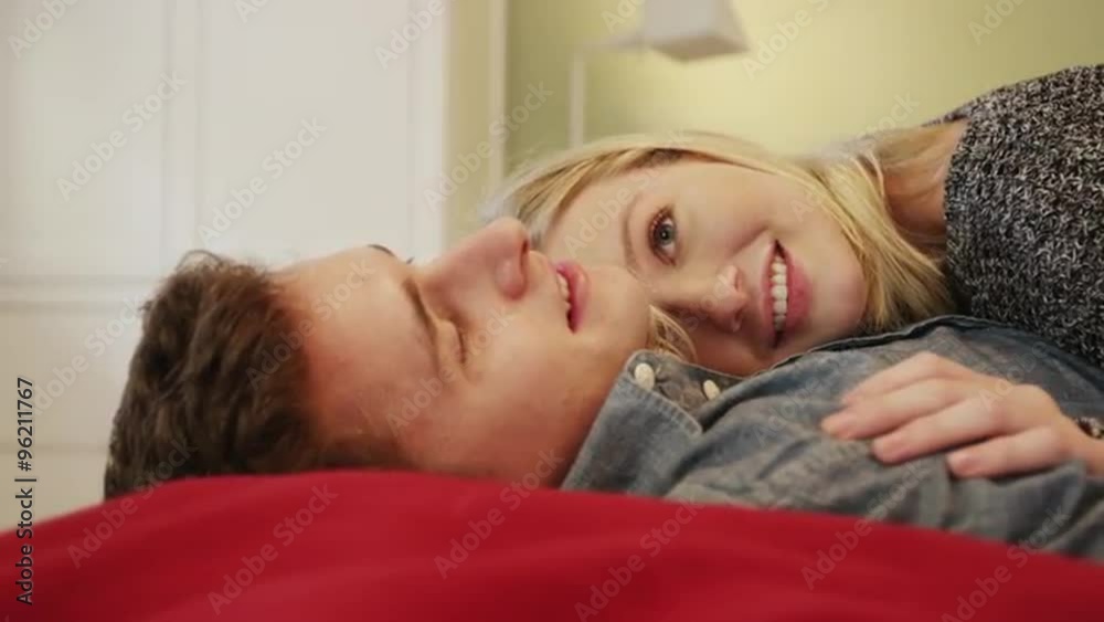 Happy young couple cuddling in bed together Happy young couple cuddling in bed together