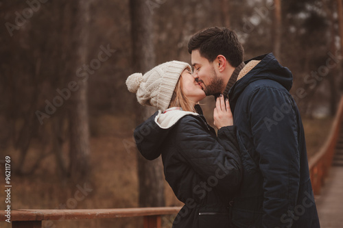 lifestyle capture of happy couple kissing outdoor on cozy warm walk in forest