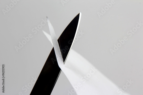 Leinwand Poster blade of a sharp knife cut across the white paper