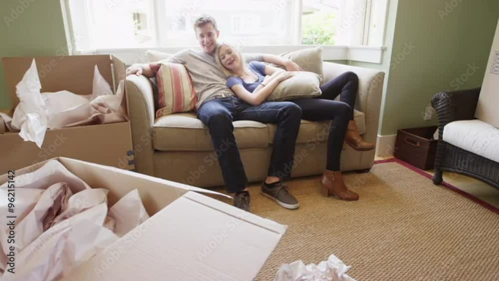 Young couple relaxing on couch after unpacking into new apartment Young couple relaxing on couch after unpacking into new apartment