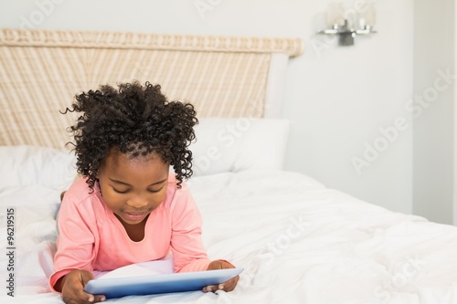 Young girl using tablet on bed 
