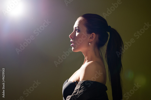 Portrait of sexy beautiful young lady looking forward on light flare copy space background