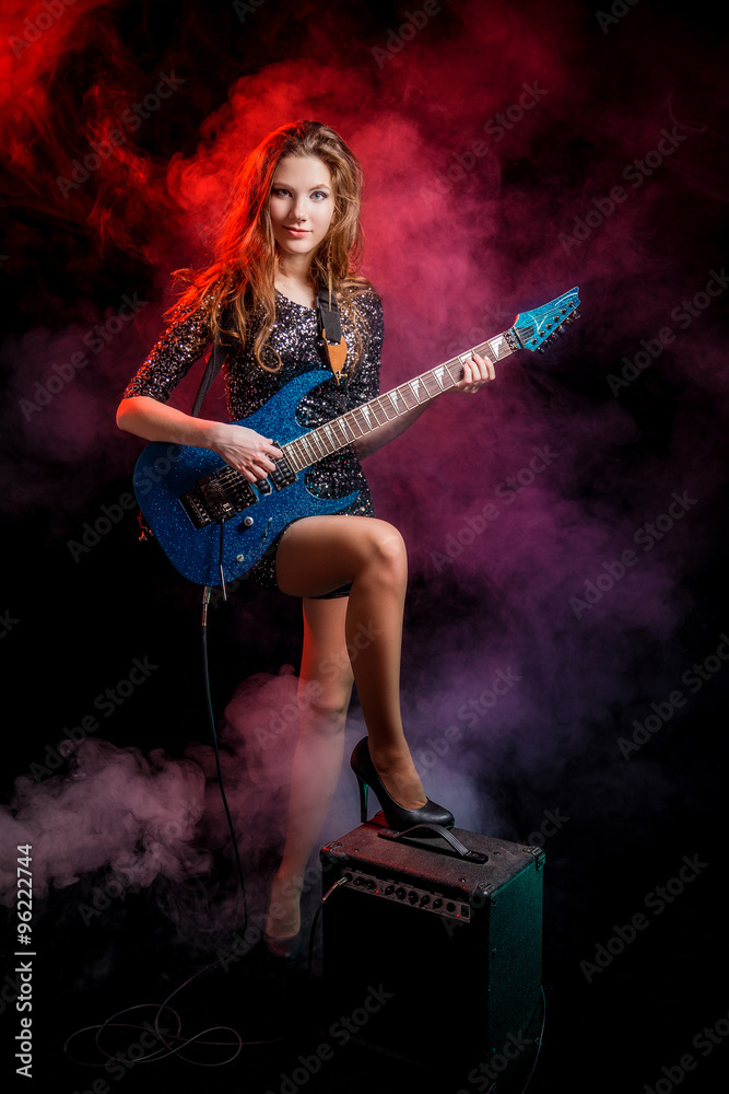 Молодая роскошная девушка с гитарой в дыму 
