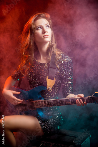 Молодая роскошная девушка с гитарой в дыму 