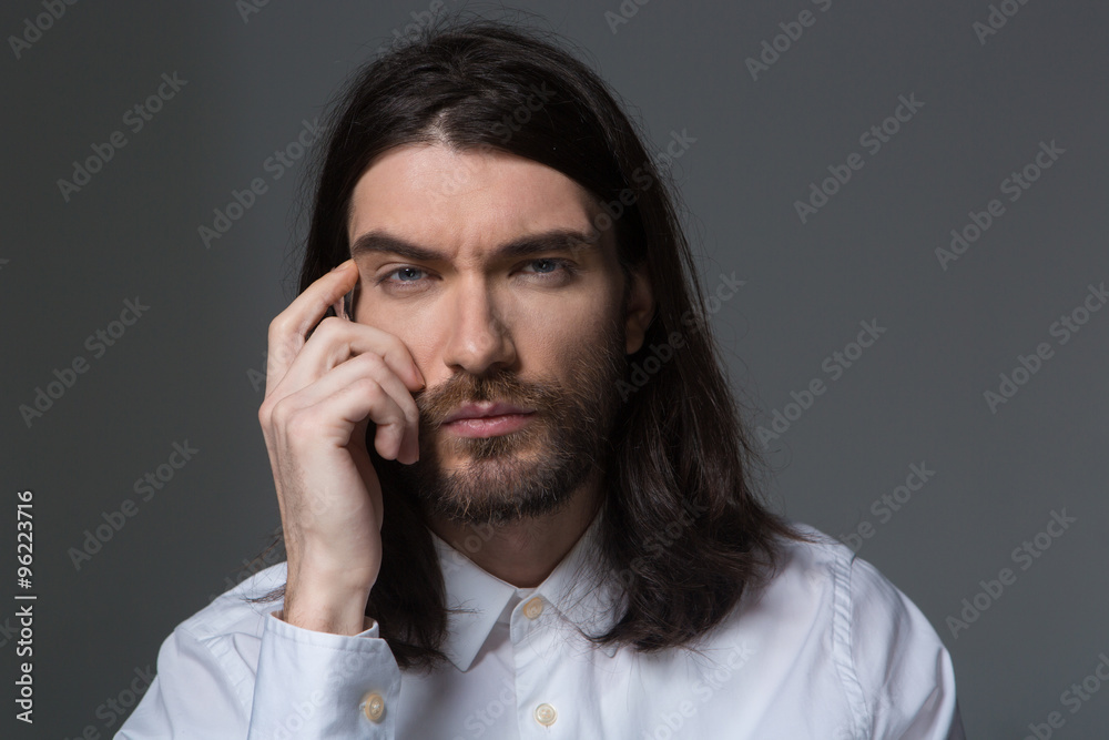 Pensive man with beard and long hair looking at camera