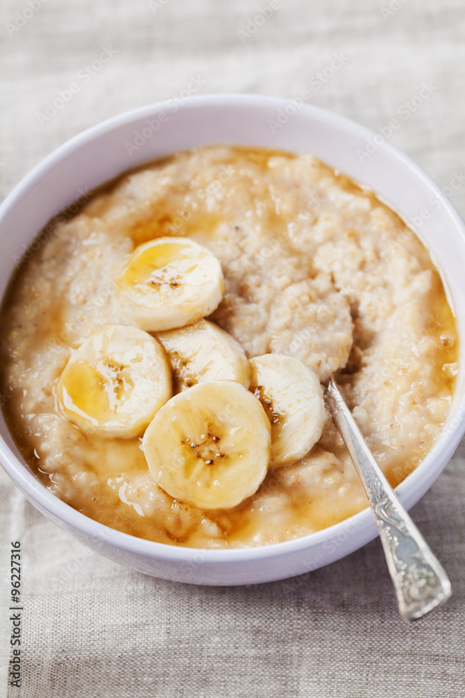 Bowl of oatmeal porridge with banana and caramel sauce on rustic table, hot and healthy breakfast every day, diet food Bowl of oatmeal porridge with banana and caramel sauce on rustic table, hot and healthy breakfast every day, diet food