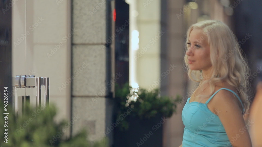 Stylish girl shopaholic looks in the windows of shops in Milan Stylish girl shopaholic looks in the windows of shops in Milan